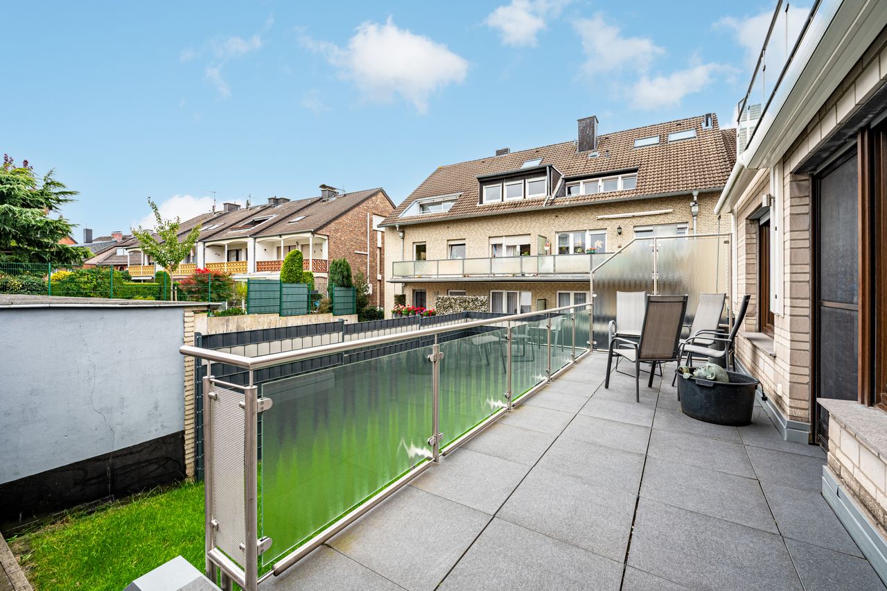 Fully furnished ground floor apartment with 2 rooms, light-filled living/dining area, separate kitchen, large terrace, lawn, and garage in a well-maintained 3-family house.